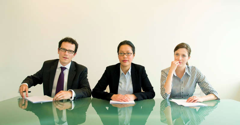 a man and two women interviewing a candidate